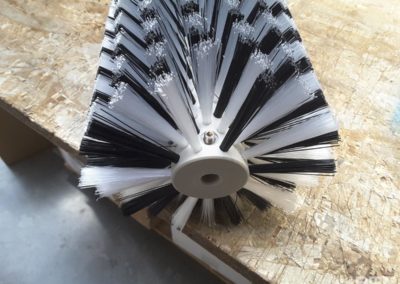 Une brosse rotative avec un garnissage composé de deux matières distinctes est présentée. Cette brosse est conçue pour être utilisée sur une machine de nettoyage de panneaux solaires.